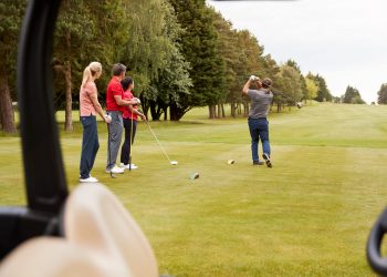 Two Couples Golfing Hitting Tee Shot Along Fairway With Driver With Buggy In Foreground two couples golfing on a course in dunnellon
